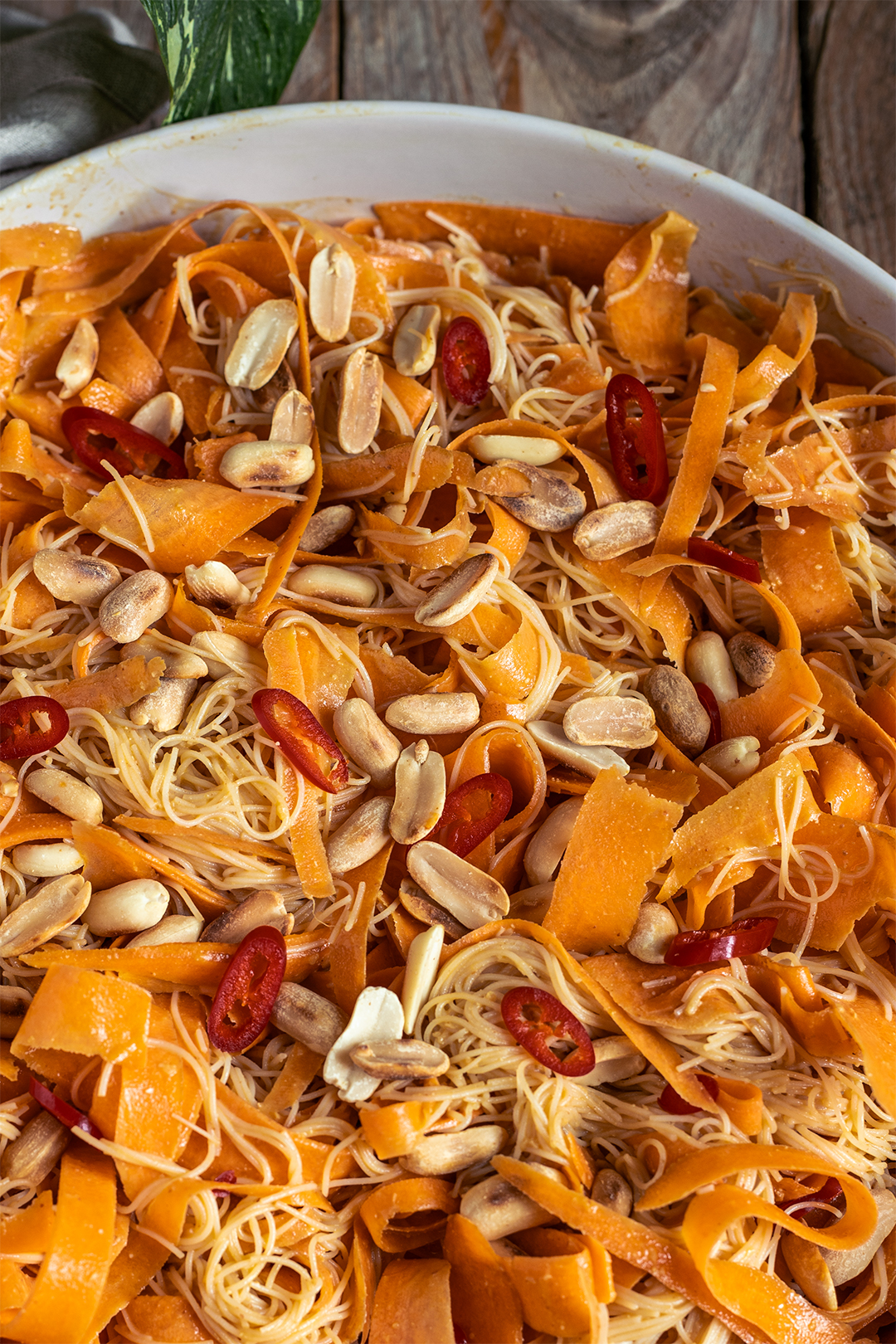 Möhren-Glasnudelsalat asiatisch in Nahaufnahme: gehobelte Karottenbänder, Glasnudeln und Erdnusssauce mit Chili-Topping