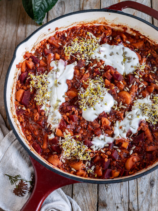 Rote Bete Linsen Pfanne, vegan, in der Pfanne serviert mit Pflanzenjoghurt, Brokkolisprossen und gerösteten Sonnenblumenkernen