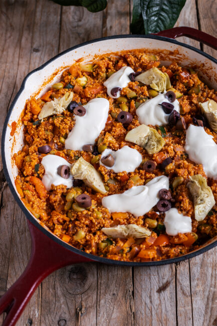 Vegane Couscous-Pfanne mit Gemüse, Edamame, Oliven und Artischocken in einer weiten Pfanne