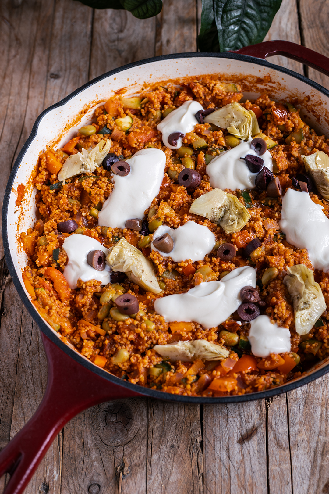 Vegane Couscous-Pfanne mit Gemüse, Edamame, Oliven und Artischocken in einer weiten Pfanne