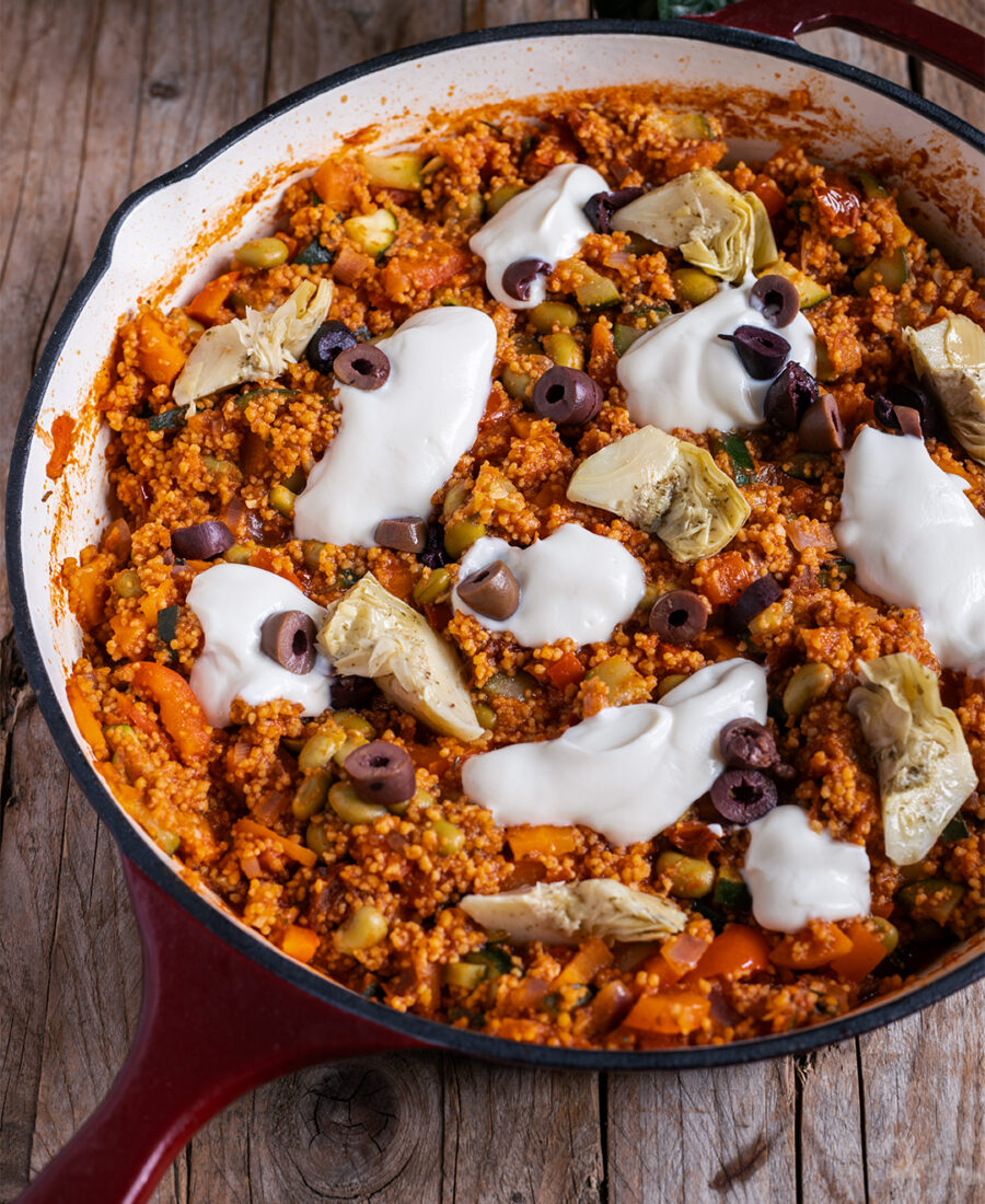 Vegane Couscous-Pfanne mit Gemüse, Edamame, Oliven und Artischocken in einer weiten Pfanne